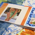 An illustrated book with model wearing summery outfit lays on colourful textiles surface