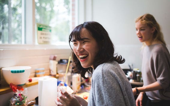 Two students laughing in a kitchen while cooking