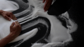 Hands moving salt around on a black background + text: ”to divide and set boundaries?”