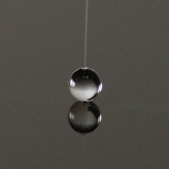 Closeup image of a water droplet being probed by a glass needle.