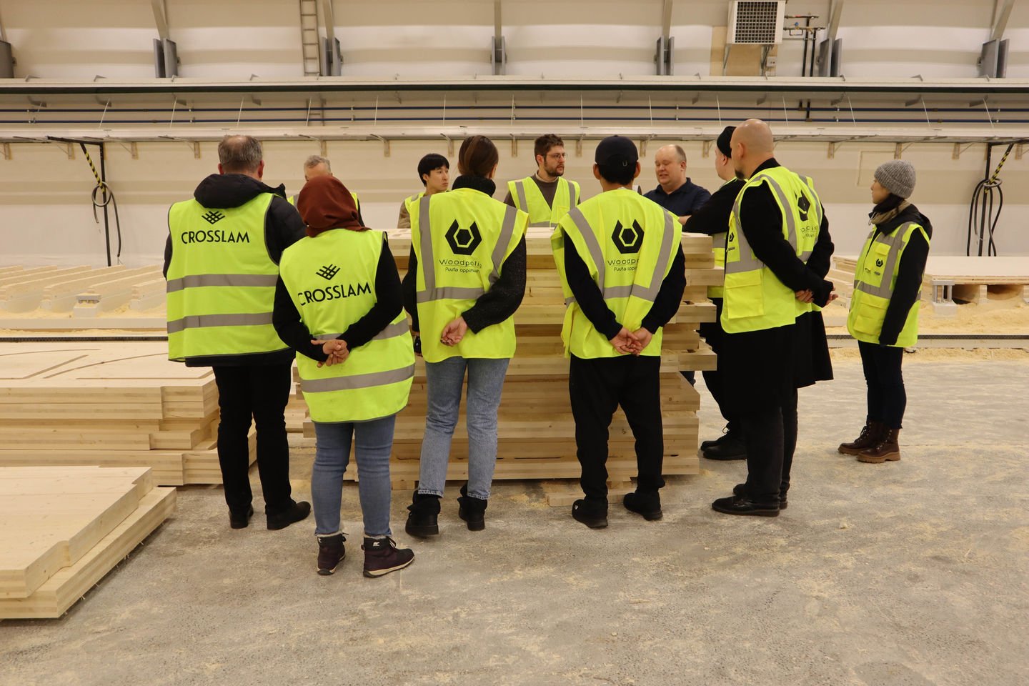 Students standing around a pile of CLT in the Crosslam factory hall
